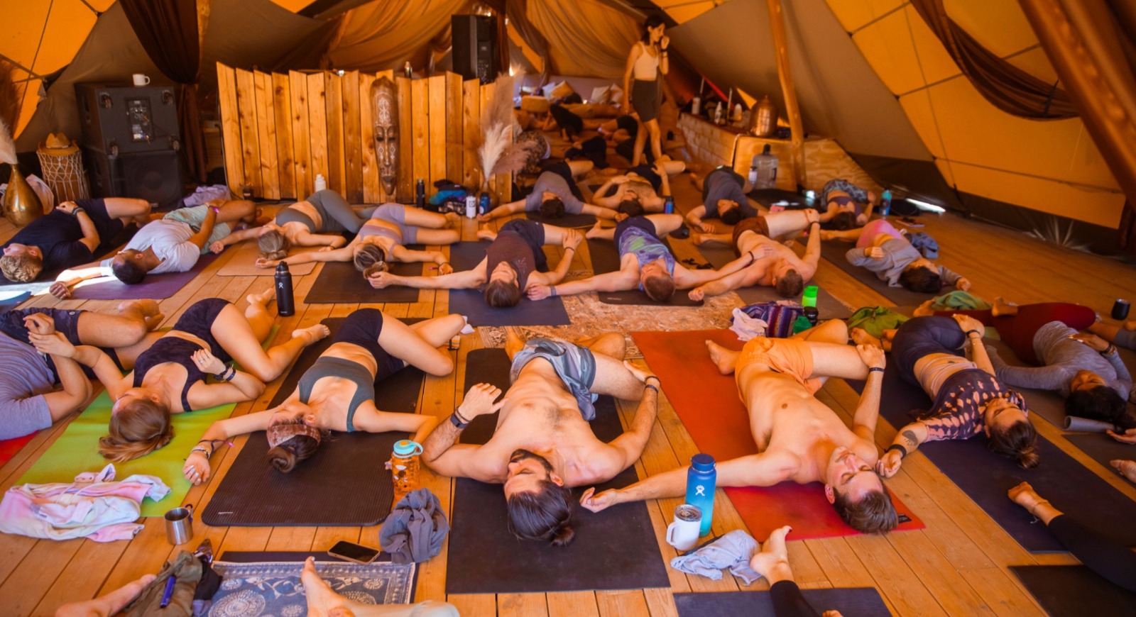 Group resting in savasana inside a warm-lit tent